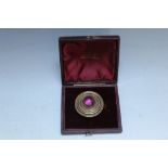 A CABOCHON AMETHYST SET GILT METAL MOURNING BROOCH, with integral hair panel to the reverse, Dia 3.5