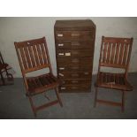 AN OAK PANELLED EIGHT DRAWER STORAGE CHEST AND TWO FOLDING HARDWOOD CHAIRS
