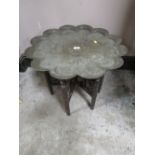 A VINTAGE EASTERN BRASS TOPPED TABLE ON CARVED FOLDING STAND