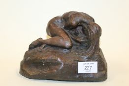 A BRONZE EFFECT STUDIO POTTERY SCULPTURE OF A FEMALE NUDE ON A ROCK SIGNED E. CAVACOS