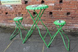 A METAL 'HEINEKEN' TABLE AND TWO STOOLS IN THE SHAPE OF BOTTLE TOPS