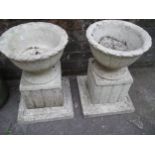 A PAIR OF CONCRETE GARDEN PLANTERS ON PLINTHS