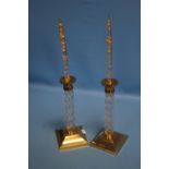 A PAIR OF BRASS AND GLASS CANDLESTICKS WITH DECORATIVE CANDLES