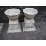 A PAIR OF TWO CONCRETE GARDEN PLANTERS ON PLINTHS