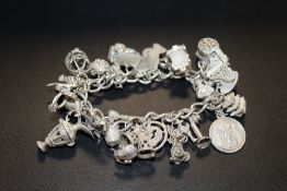 A HALLMARKED SILVER CHARM BRACELET APPROX WEIGHT - 87G