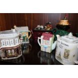 A COLLECTION OF SEVEN NOVELTY CERAMIC TEAPOTS TO INCLUDE AN EASTENDERS QUEEN VIC EXAMPLE,