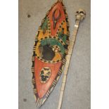 A TRIBAL STYLE CARVED WOODEN SHIELD H - 126CM , TOGETHER WITH A SKULL TOPPED MODERN WOODEN STAFF