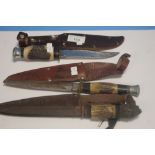 THREE VINTAGE ANTLER GRIP HUNTING KNIVES IN LEATHER SHEATHS (3)
