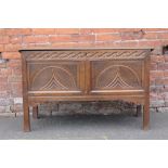 AN EARLY 18TH CENTURY OAK CARVED COFFER, the hinged lid above a heavily carved two panel front,