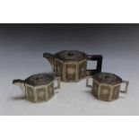 AN UNMARKED WHITE METAL OCTAGONAL THREE PIECE BACHELORS TEA SET, having decorated panels and angular