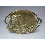 A BRASS ART NOUVEAU TRINKET DISH, embossed with a female head in side profile against a riverside