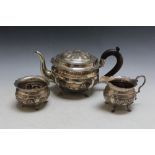 AN UNMARKED WHITE METAL CONTINENTAL THREE PIECE TEA SERVICE, decorated with typical Asian village