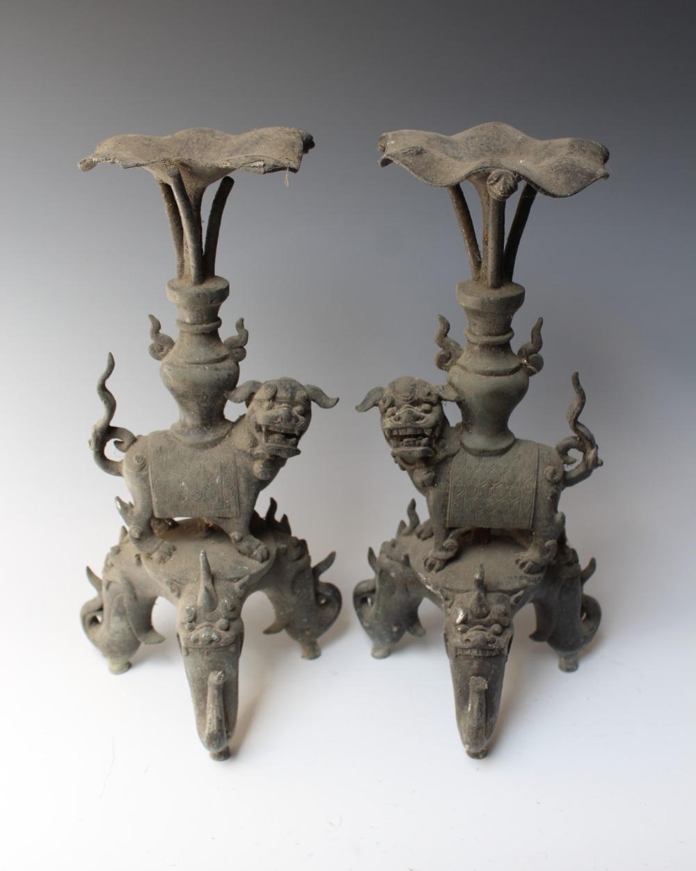 A PAIR OF 19TH CENTURY CAST BRONZE FOO DOG STANDS, each raised on three scrolling feet with foo