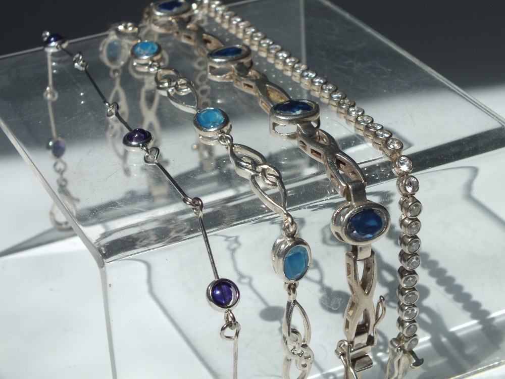 THREE MODERN SILVER GEMSET BRACELETS, to include a diamante set tennis bracelet, together with an