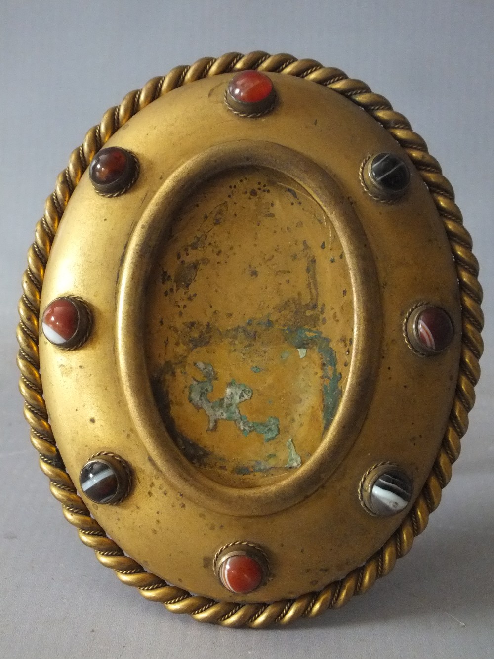 AN ANTIQUE GILT METAL OVAL PICTURE FRAME, having various polished agate cabochon embellishments to