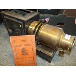 AN ANTIQUE MAGIC LANTERN WITH BRASS LENSE AND AN INSTRUCTION BOOKLET