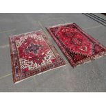 AN EASTERN WOOLLEN RUG ON A RED GROUND 146 X 107 CM TOGETHER WITH ANOTHER LARGER RED WOOLLEN RUG (