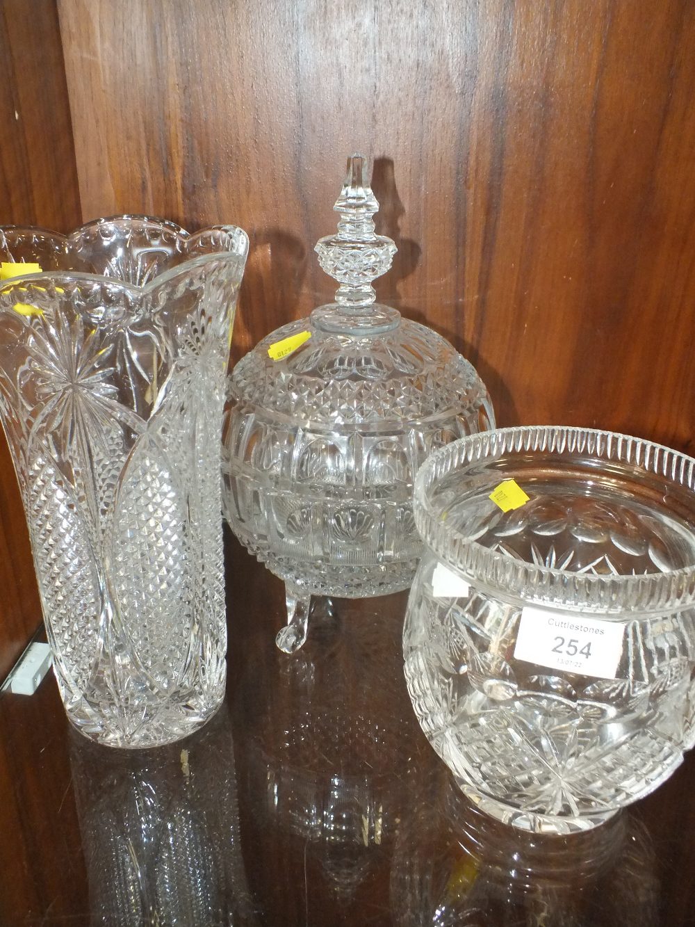 A CUT AND PRESSED GLASS LIDDED BOWL TO SCROLLED FEET, TOGETHER WITH A CUT AND PRESSED GLASS VASE AND