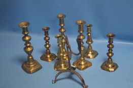 A RUSHLIKE HOLDER AND A QUANTITY OF BRASS CANDLESTICKS