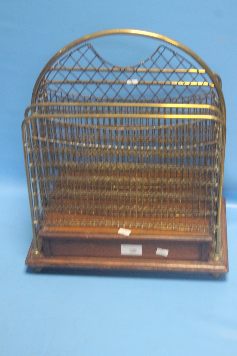 AN EDWARDIAN BRASS AND OAK 4 SECTION NEWSPAPER RACK WITH WIRE WORK PANELS