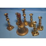 A WOODEN HANDLED BRASS BELL AND A QUANTITY OF BRASS CANDLESTICKS