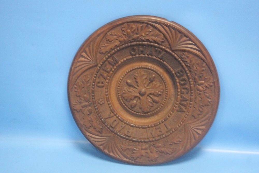 A CARVED CIRCULAR WOODEN PLAQUE WITH INSCRIPTION