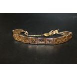 A 9CT ROSE GOLD GATE BRACELET WITH TWO UNMARKED YELLOW METAL CHARMS