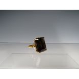 AN UNMARKED YELLOW METAL DRESS RING, set with a large emerald cut smoky quartz, ring size 0 3/4,