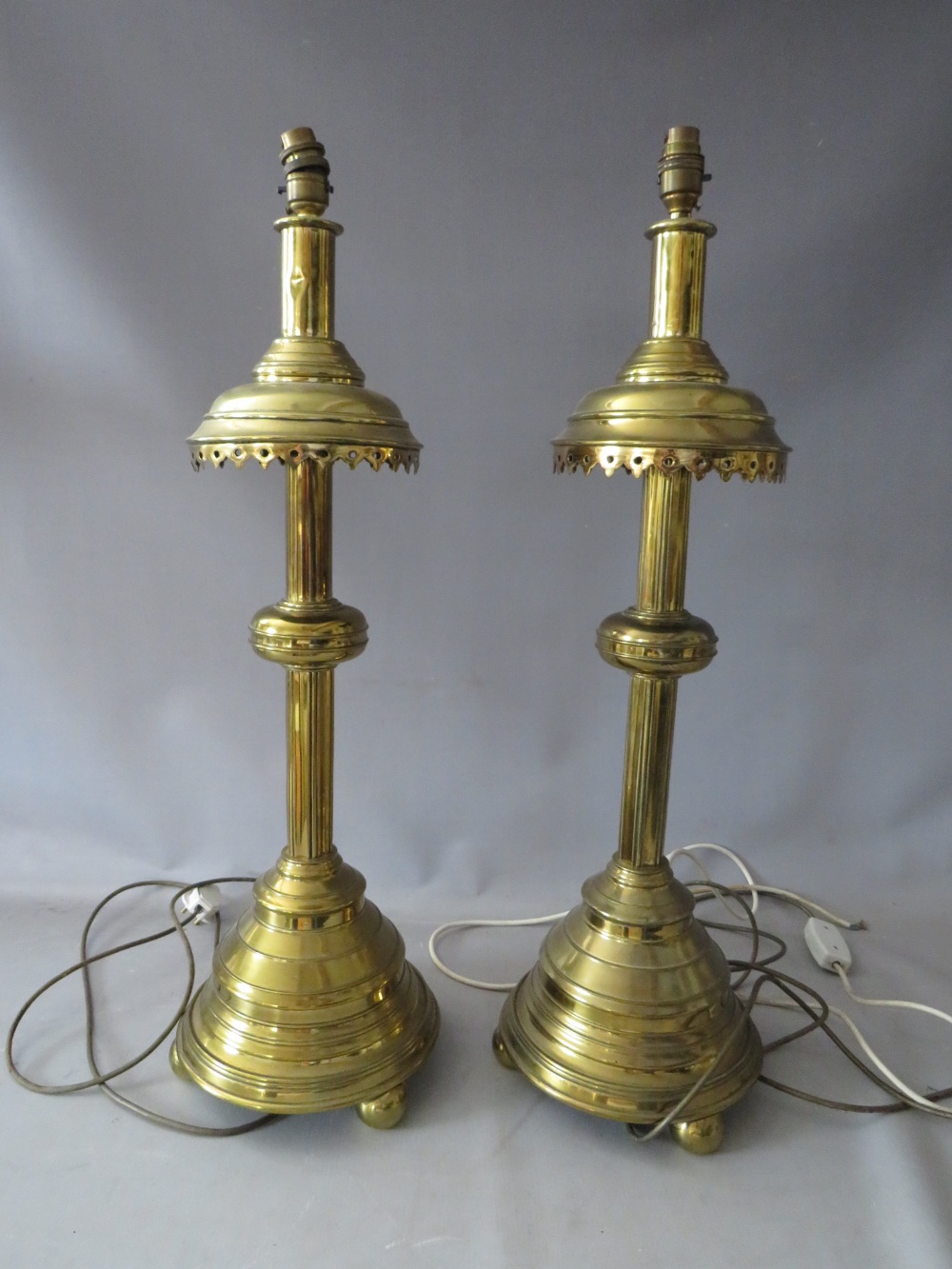 A PAIR OF EARLY 20TH CENTURY HEAVY BRASS ECCLESIASTICAL STYLE CANDLE STANDS CONVERTED TO TABLE