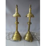A PAIR OF EARLY 20TH CENTURY HEAVY BRASS ECCLESIASTICAL STYLE CANDLE STANDS CONVERTED TO TABLE