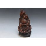 A CARVED CHINESE FIGURE OF A BUDDHA HARVESTING on matched stand, figure H 18 cm