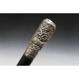 A NOVELTY EBONISED WALKING CANE, with white metal handle detailed with mythical beasts amongst the