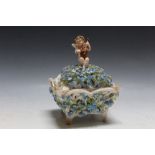 A DELICATE FLORAL PORCELAIN PIERCED BOX TOPPED WITH A PUTTI PLAYING A VIOLIN, raised on four feet,