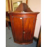 AN ANTIQUE BOW FRONTED HANGING CORNER CUPBOARD
