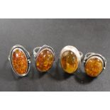 A COLLECTION OF FOUR MODERN AMBER DRESS RINGS