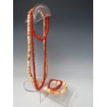 AN AFRICAN CORAL TYPE GLASS TRADE BEAD NECKLACE AND TWO BRACELETS, together with a larger example