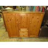 A MODERN HONEY PINE STORAGE CUPBOARD WITH A COMBINATION OF CUPBOARDS AND DRAWERS APPROX W-142 CM