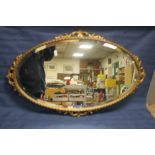 AN OVAL GILT ORNATE MIRROR 75 CM X 48 CM