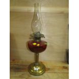 A VINTAGE BRASS AND RUBY GLASS OIL LAMP