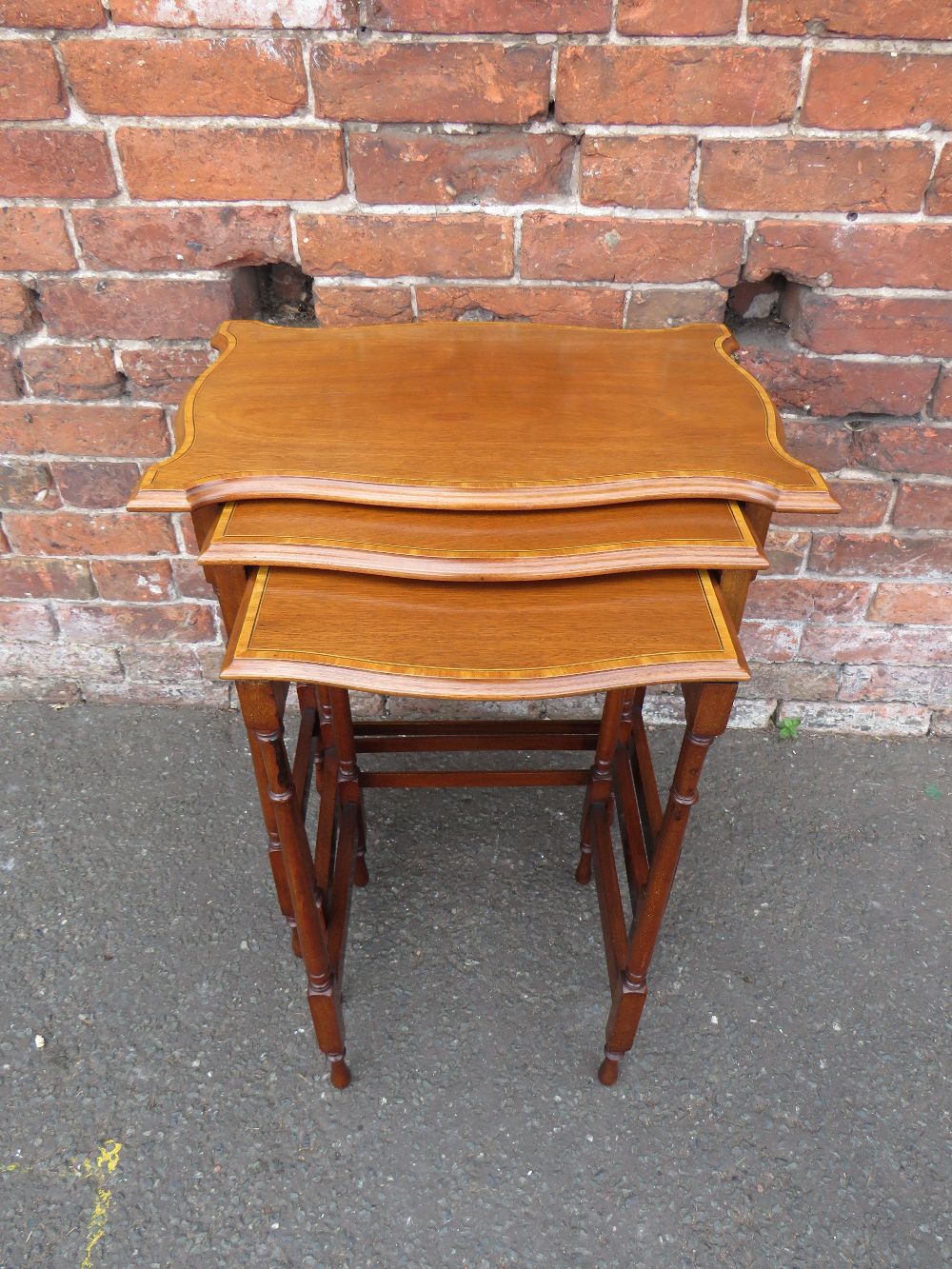AN EDWARDIAN MAHOGANY NEST OF TABLES, the shaped tops with satinwood banding, H 71 cm, W 54 cm