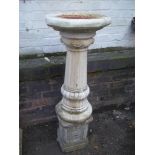 A RECTSITUTED STONE BIRD BATH ON CONCRETE PLINTH