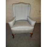AN ANTIQUE UPHOLSTERED WING BACK CHAIR WITH QUEEN ANNE LEGS