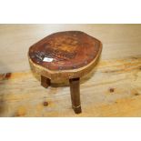 A VINTAGE OAK MILKING STOOL WITH LEATHER TOP HAVING SAIL SHIP DETAIL