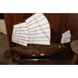 A WOODEN MODEL OF AN ORIENTAL JUNK ON STAND WITH MATERIAL SAILS