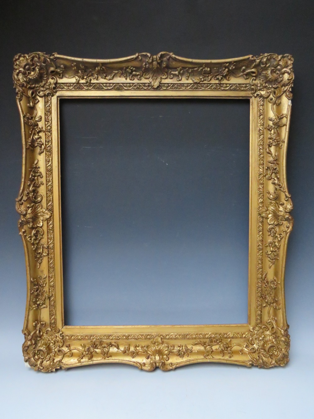 A 19TH CENTURY DECORATIVE GOLD SWEPT FRAME, frame W 9 cm, rebate 62 x 51 cm