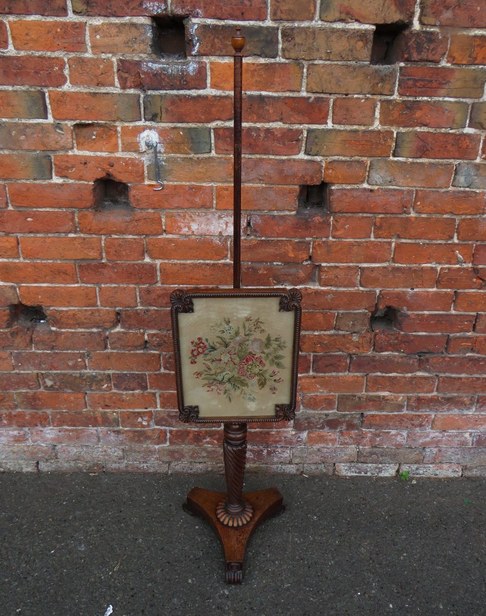 A 19TH CENTURY MAHOGANY POLE SCREEN, having a shaped glazed needlepoint adjustable floral screen,