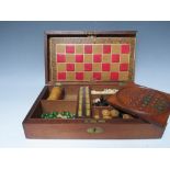 A VINTAGE WOODEN GAMES BOX AND CONTENTS, the contents to include miniature bone dominoes, chess