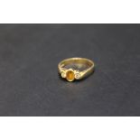 A HALLMARKED 18 CARAT GOLD RING, set with yellow sapphire type central stone and two small diamonds,