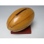 A VINTAGE WOODEN MONEY BOX IN THE FORM OF A RUGBY BALL, H 10 cm, L 12.5 cm