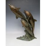 A 20TH CENTURY BRONZED STYLE MODEL OF THREE DOLPHINS AT PLAY, mounted on a naturalistic wave plinth